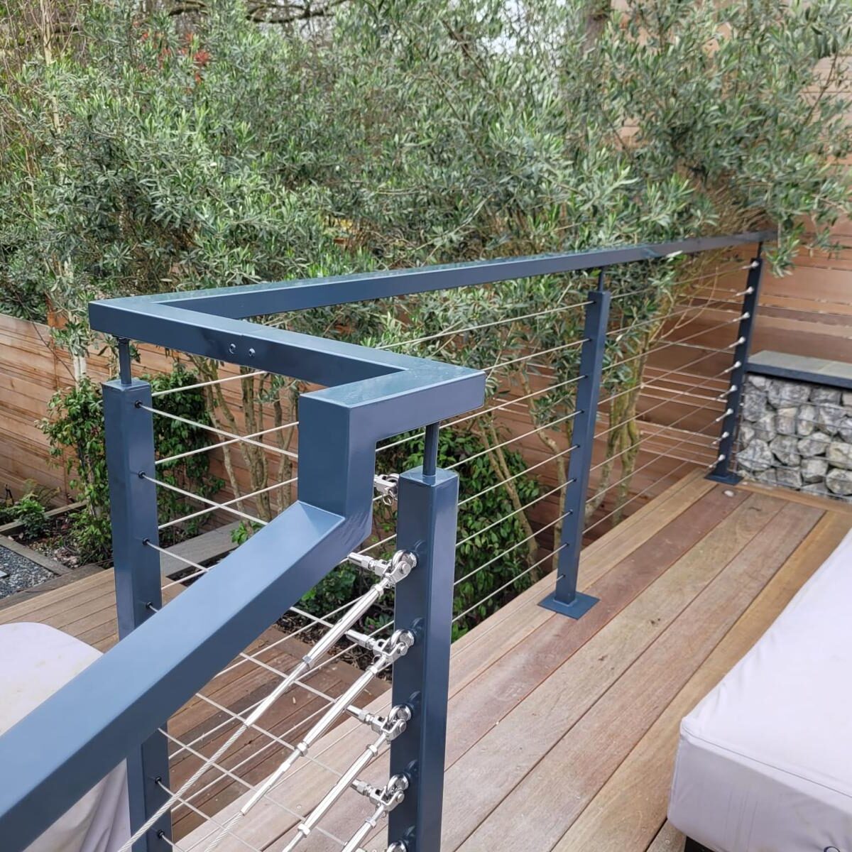 Wire Balustrade Systems 1 Close-up view of a modern post and wire balustrade system with sleek metal posts and cables, installed on a wooden deck, enhancing safety and adding a contemporary touch to the outdoor area.