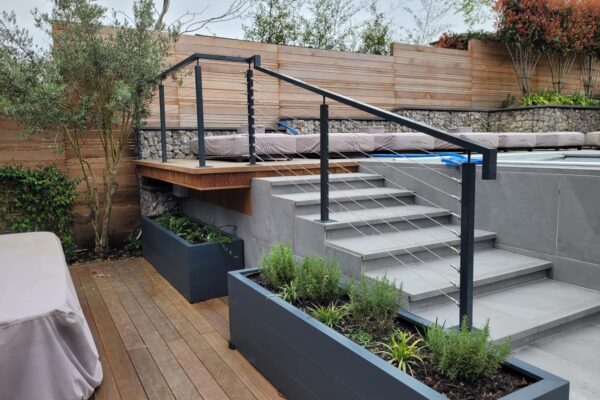 Modern outdoor deck featuring a post and wire balustrade system with sleek metal posts and cables, enhancing the contemporary design of the multi-level terrace and providing safety and style.