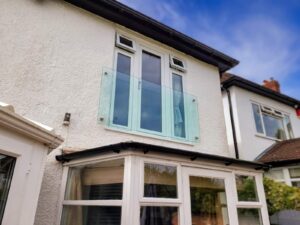 Frameless Juliet balcony installed on a white residential home in Wolverhampton, featuring four stainless steel glass adaptors and toughened safety glass.