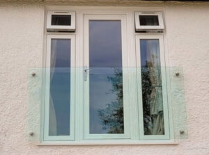 Close-up view of the frameless Juliet balcony with four glass adaptors, showcasing the clear toughened glass in front of white doors