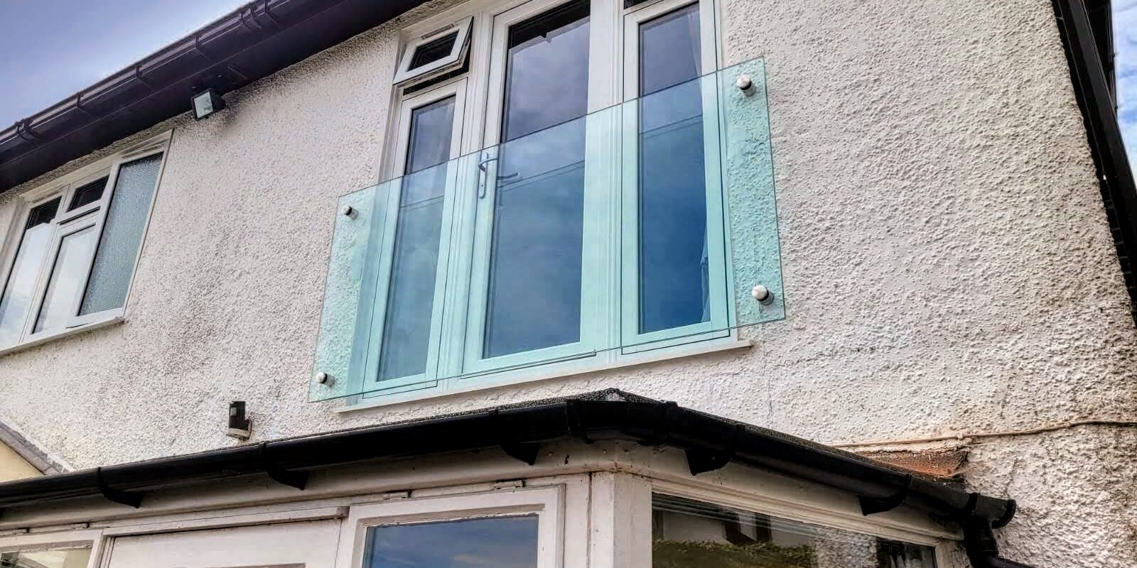 ide view of the frameless Juliet balcony on a modern home in Wolverhampton, highlighting the minimalistic design and secure glass adaptors.