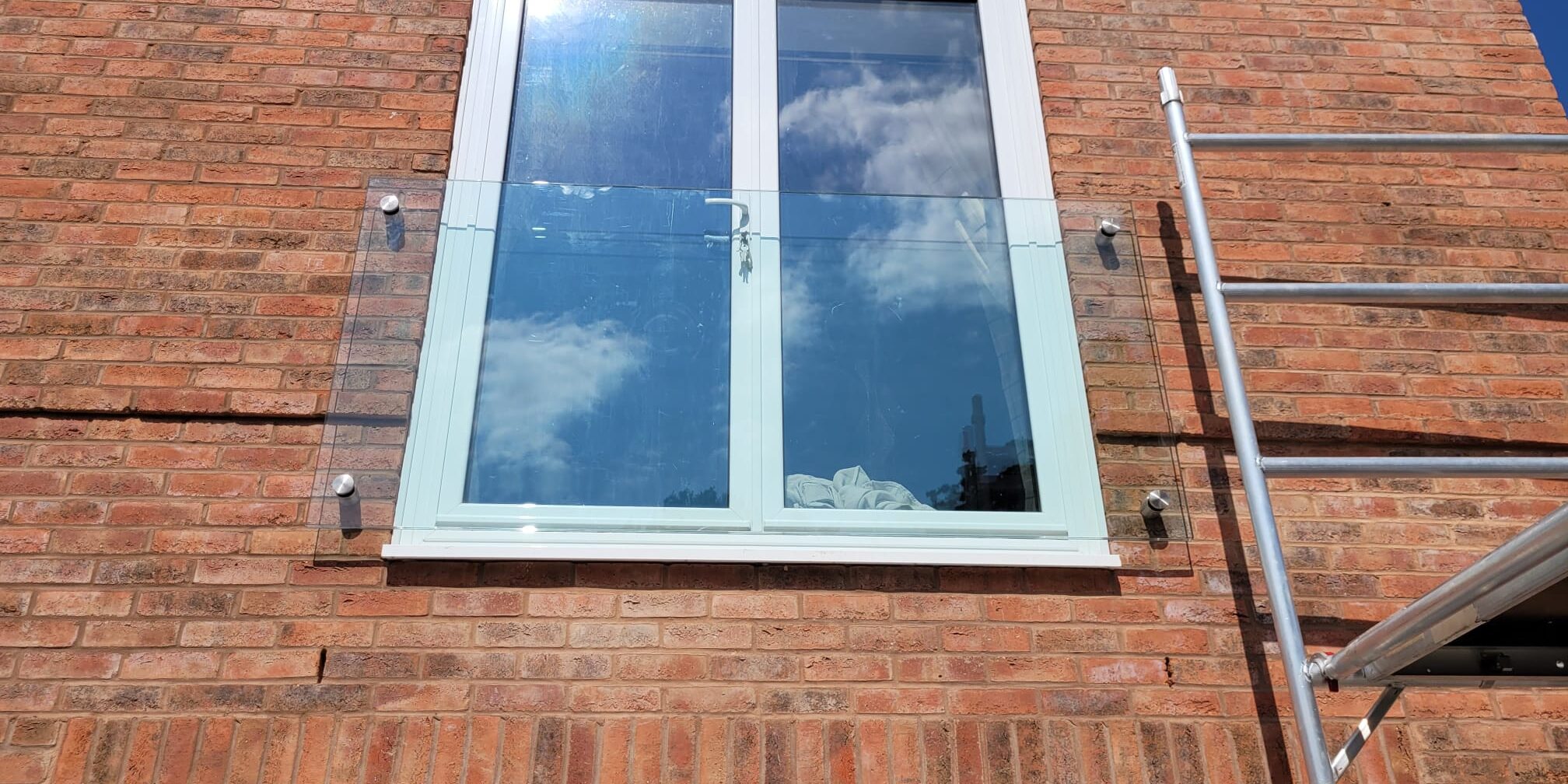 Frameless Juliet balcony installation in Rugby with clear toughened glass secured by stainless steel adaptors.