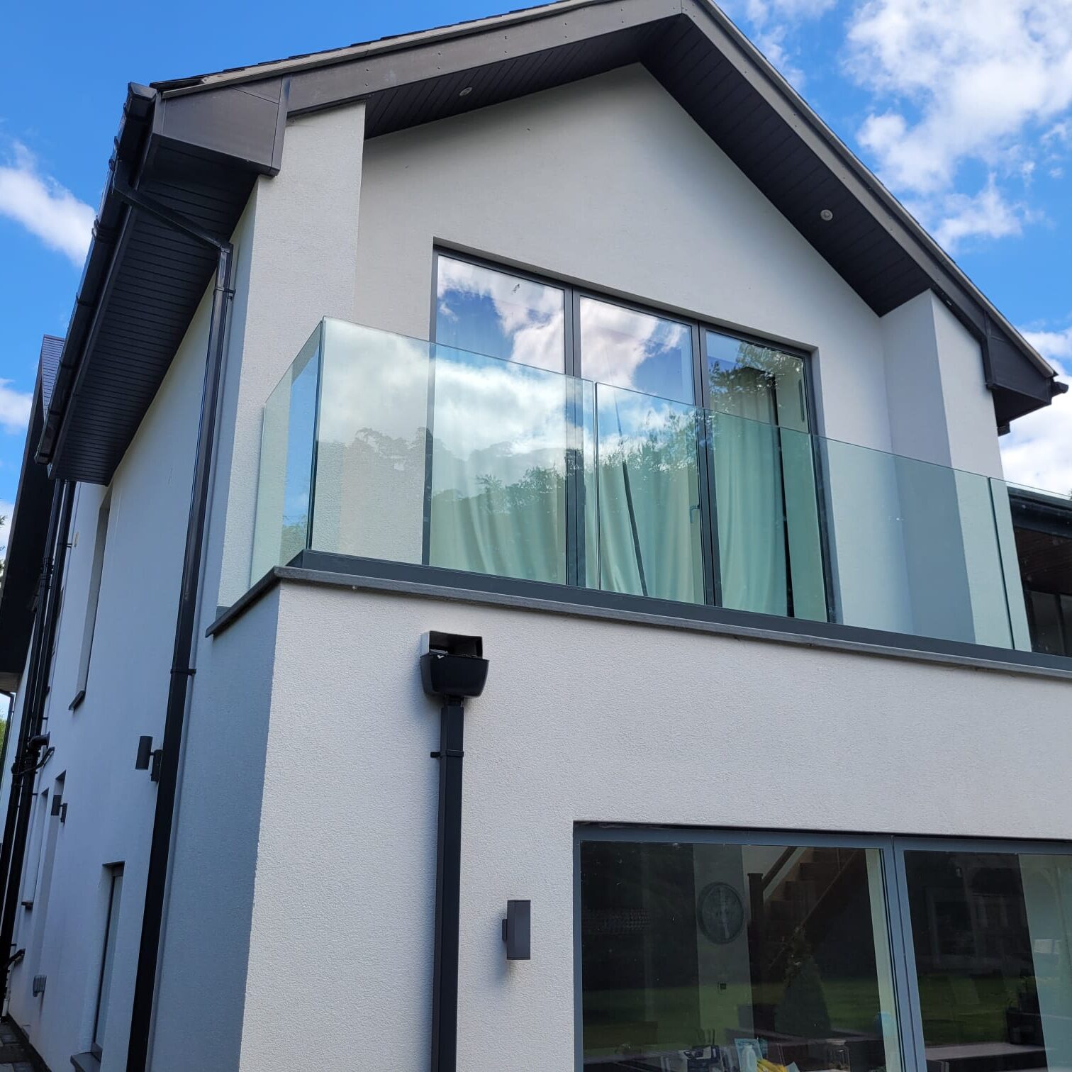 Frameless Glass Balustrades 2 Side view of a modern house featuring a frameless glass balustrade with a gray powder-coated base fixed track, providing safety and style.