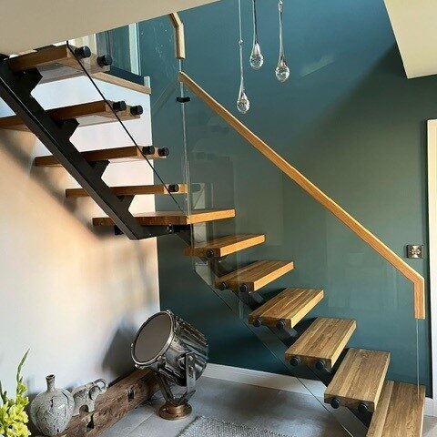 staircase Modern floating glass steel staircase with single spine steel structure, oak timber treads, and seamless glass balustrades, creating a minimalist yet striking focal point in a contemporary home.