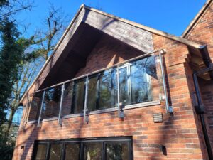 Frameless Juliet balcony installed on a brick home in Telford, allowing maximum light and ventilation.