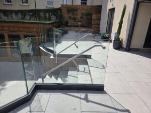 frameless glass balustrade overlooking garden with stainless steel handrail support