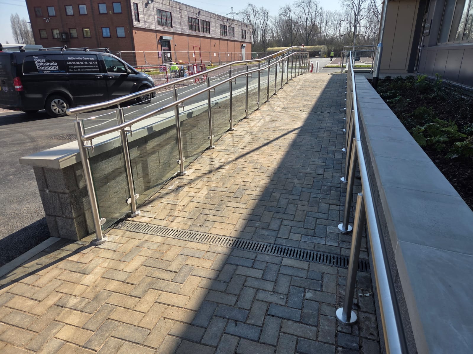 Side view of glass balustrade ramp system with 316 stainless steel posts and handrail in Northampton project