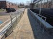 Long run of glass balustrade ramp with stainless steel handrail and posts alongside commercial building in Northampton